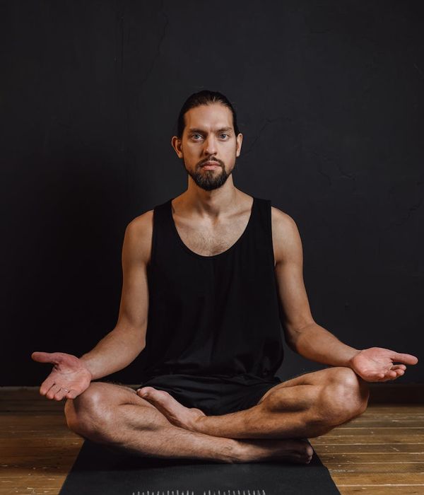 Man in a focused strength pose, demonstrating control and stability in a dark minimalist setting.